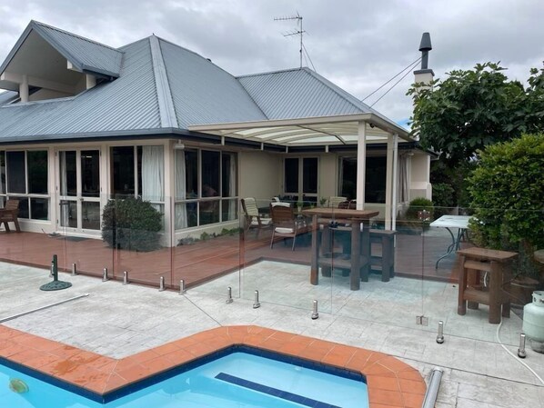 Uma casa com alpendre, piscina e jardim.