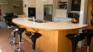 Una cocina moderna con una isla central, taburetes de bar, un refrigerador, microondas y un lavaplatos.