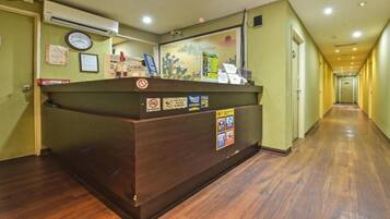 A reception desk with a clock, a 'Welcome' sign, and various informational posters.