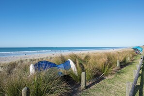Ein Strand mit einem Holzzaun und einem blauen Schild im Vordergrund.