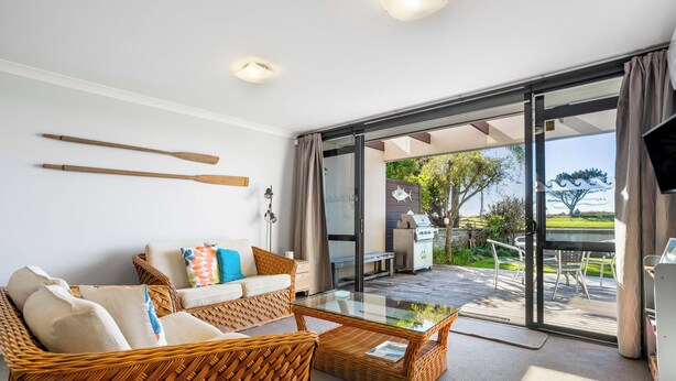 Una sala de estar moderna con una mesa de centro de vidrio, muebles de mimbre y vistas al exterior.