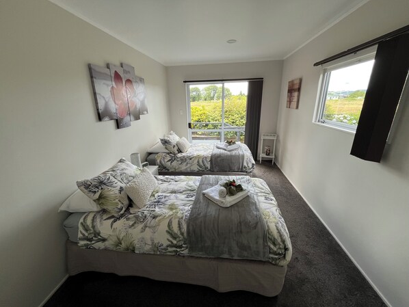 A bedroom with two beds, a window with a view of greenery, and a small table with a tray.