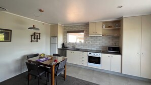 A compact kitchen with a dining area, featuring a refrigerator, stove, microwave, and a window providing natural light.