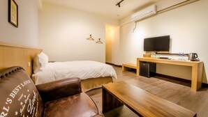 Ett hotellrum med en säng, ett skrivbord i trä, en tv och en bänk.