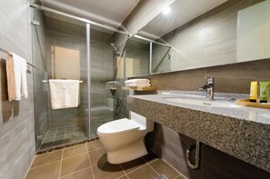 A modern bathroom with a glass-enclosed shower, a white toilet, and a granite countertop with a mirror above. - Anping 1923 Homestay (Tainan)