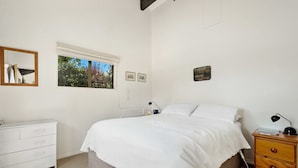 Un dormitorio con cama, mesita de noche, cómoda, ventana y decoración en las paredes.