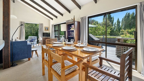 Un comedor con una mesa de madera dispuesta para cuatro personas, rodeada de sillas de madera.
