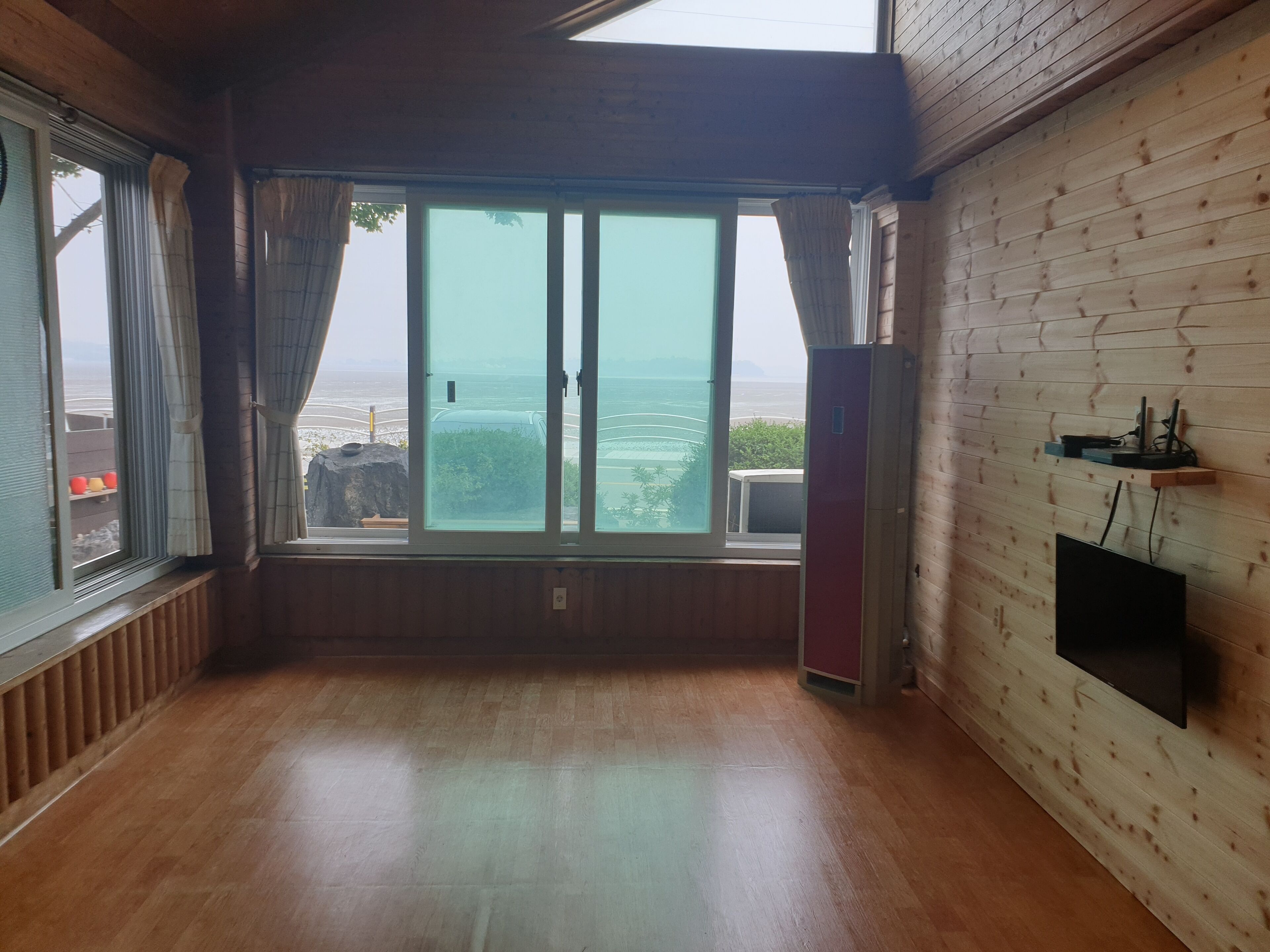 A room with a large sliding glass door leading to a balcony with a view of the sea.