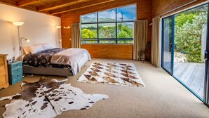 Une chambre avec une grande fenêtre, un lit, un plafond en bois et un tapis en peau de vache.
