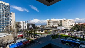 A cityscape with modern buildings, a roundabout, and a bus. - Apartment on Saakadze Square (Tbilisi)