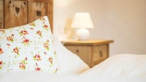 A bed with a floral pillow and a wooden headboard. - Tholer (Lagundo)