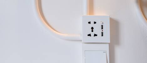 A white electrical outlet with a switch and a USB port on a white wall.