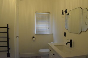 Bathroom features a toilet, sink, and mirror, with a window and door.