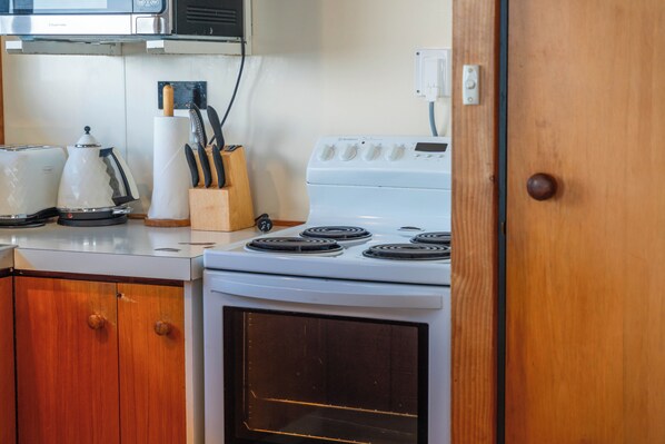 A kitchen with a stove, oven, and various appliances. - Heights Haven - Acacia Bay Holiday Home (Acacia Bay)