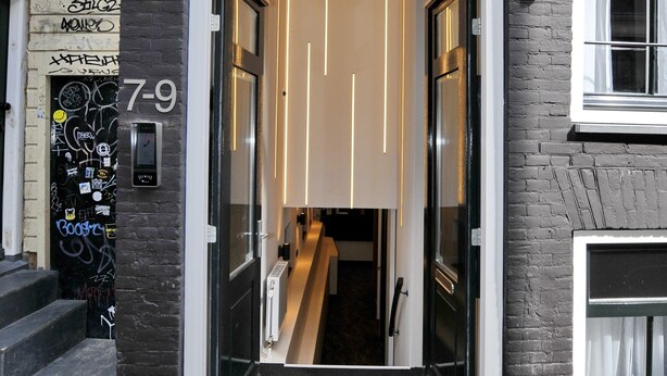 A hotel entrance with a modern design, featuring a glass door and a visible interior staircase. - Cityview Hotel (Amsterdam)