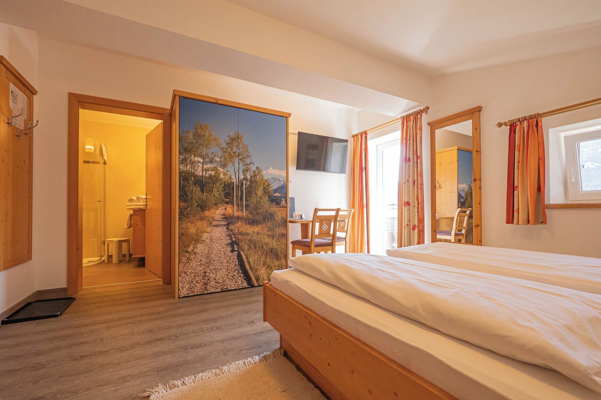 A bedroom with a wooden bed, a desk, a chair, and a large mirror.