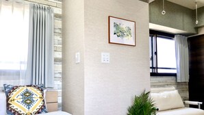 Une chambre à coucher moderne avec un lit, un canapé, une plante en pot et un luminaire fixé au mur.