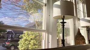 A room with large windows, a lamp, and a statue.