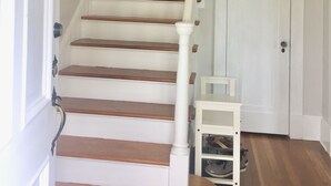 A staircase with white painted steps and wooden handrails, leading to a white door.