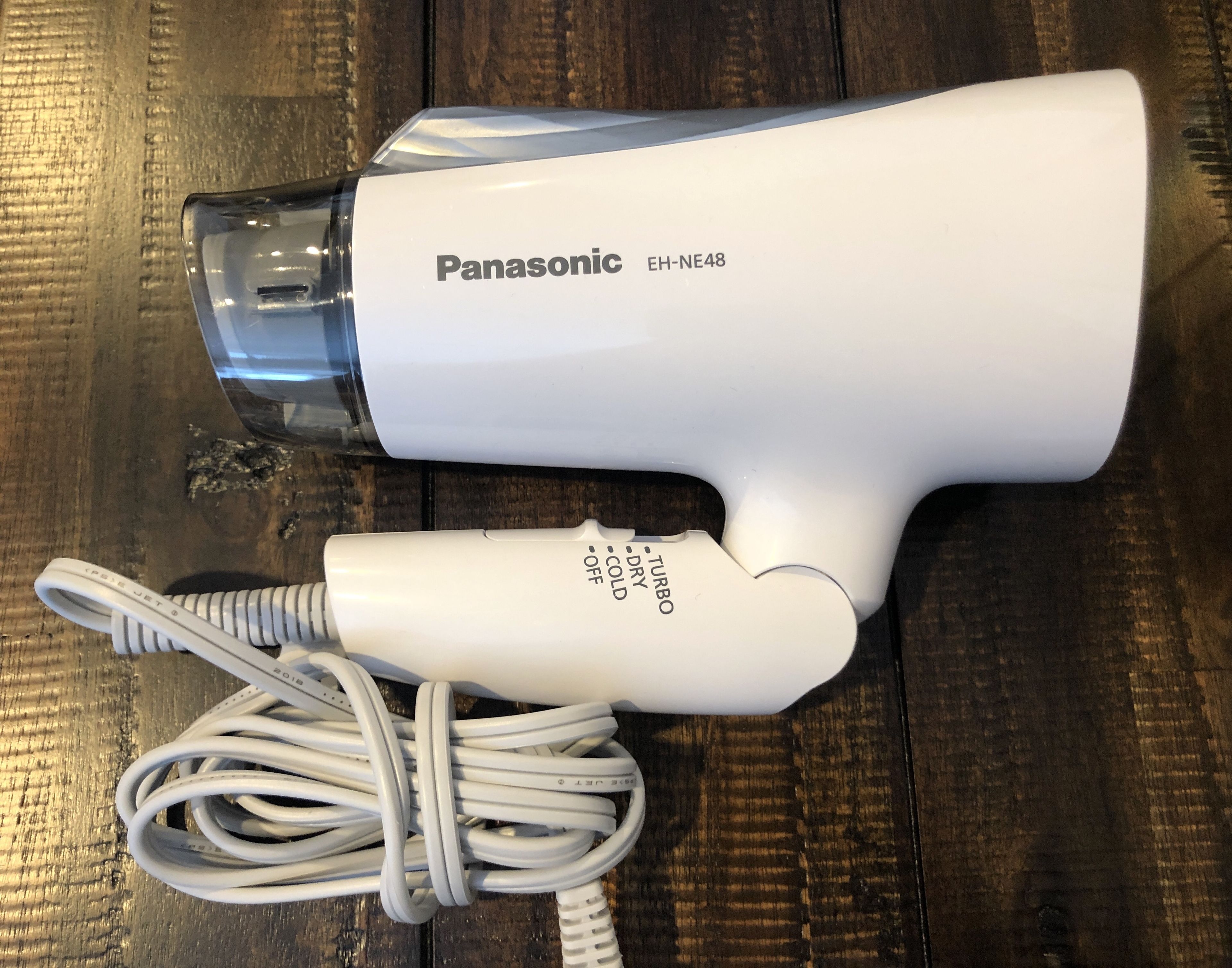 Een Panasonic EH-NE48 haardroger met snoer, op een houten ondergrond.