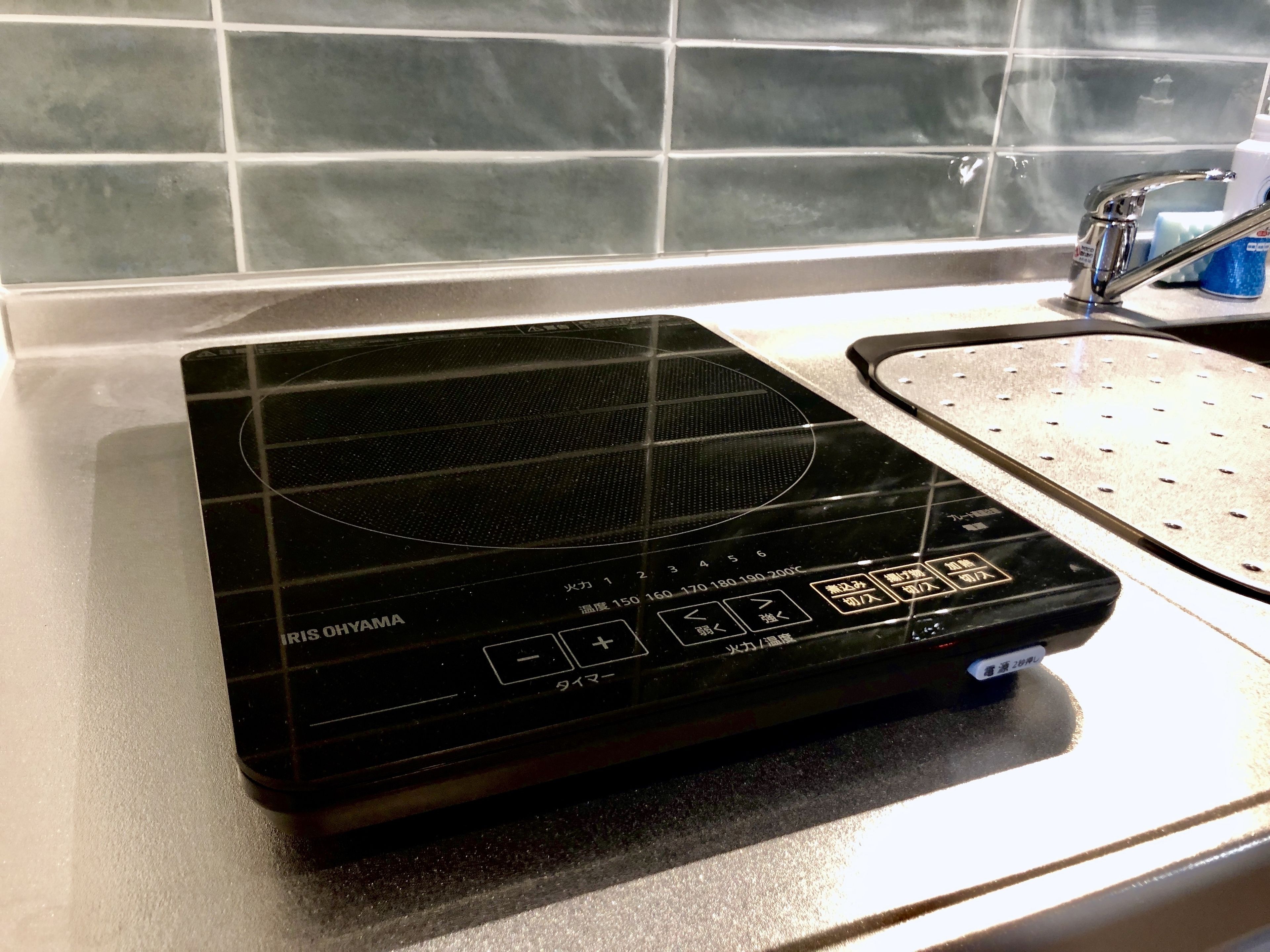 A black induction cooktop with a digital display and control buttons, placed on a kitchen countertop.