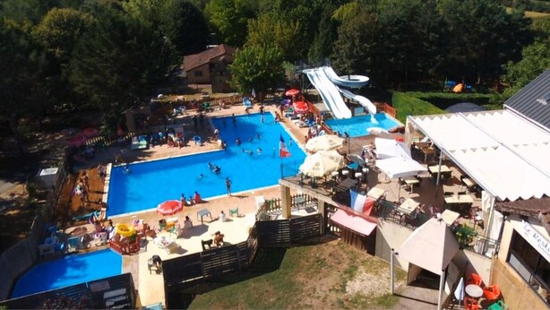A swimming pool with a water slide, surrounded by lounge chairs and umbrellas.