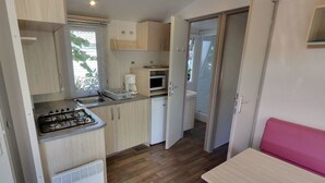 A compact kitchen with a gas stove, a coffee maker, and a microwave.