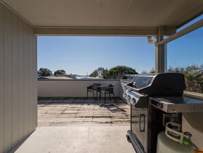 Une terrasse extérieure équipée d’un barbecue, de deux chaises et offrant une vue sur le paysage.