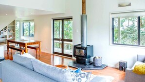 Een ruime woonkamer met een hoge plafond, een groot raam en een moderne open haard.