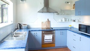 Een moderne keuken met een blauw aanrecht, roestvrijstalen apparatuur en lichtblauwe kastjes.