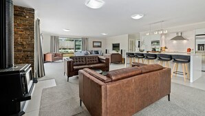 Ein modernes Wohnzimmer mit Kamin, einer Couch und einer Küchenzeile mit Barhocker.