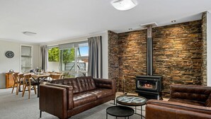 Ein Wohnzimmer mit Steinwand, Ledersofas, einem Essbereich mit Tisch und Stühlen sowie einem Kamin.