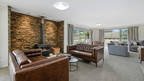 Ein Wohnzimmer mit Steinwand, Ledersofas, Kamin und großen Fenstern.