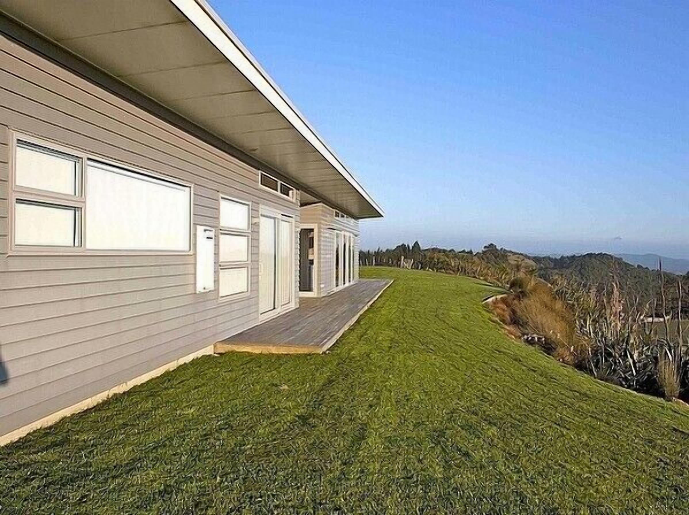 A modern single-story house with a flat roof, a covered porch, and a well-maintained lawn.