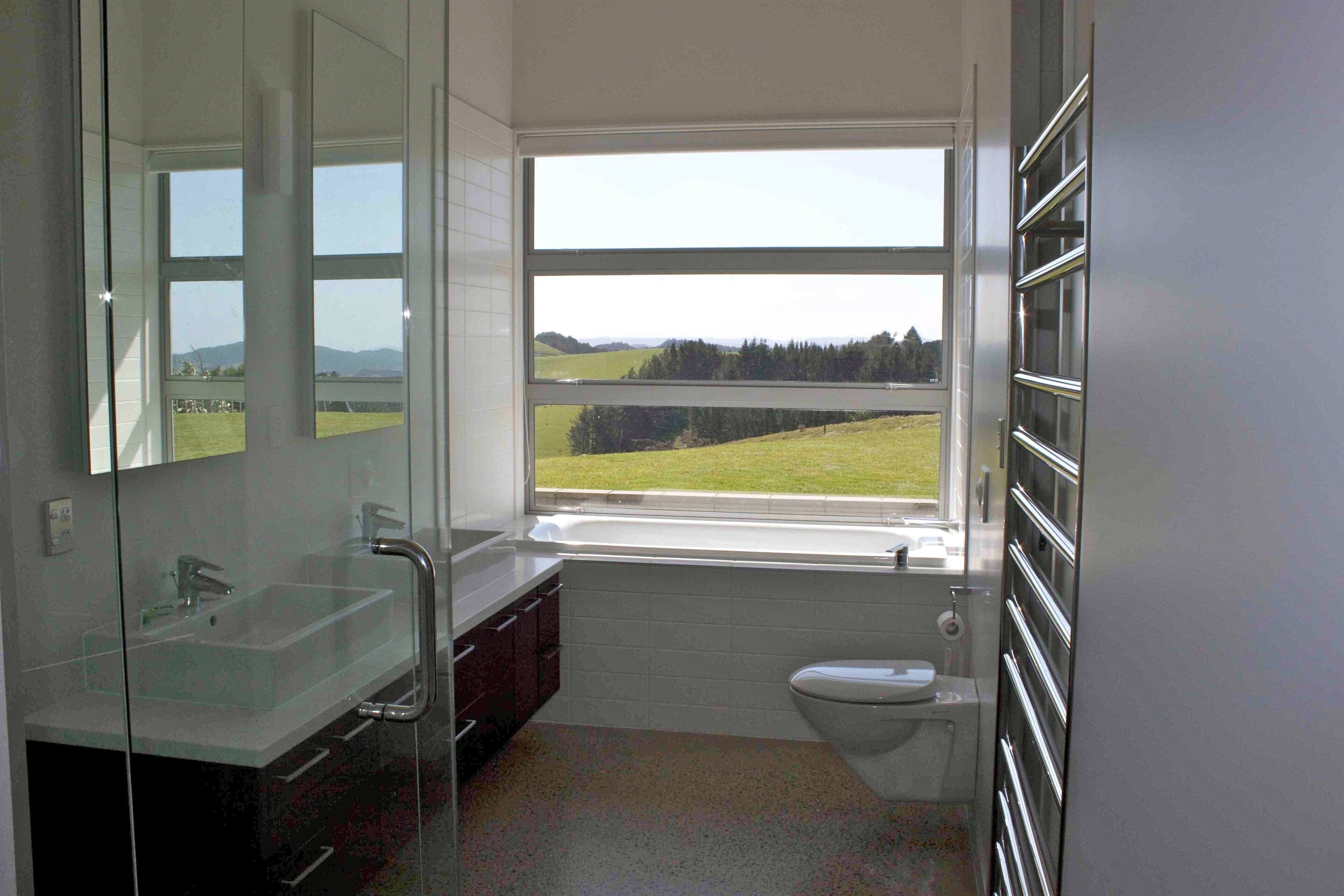 A bathroom with a large window, a sink, and a toilet.