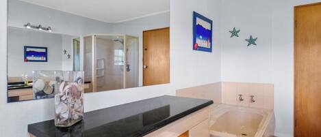 A modern bathroom with a large mirror, a bathtub, and a vanity with a sink.