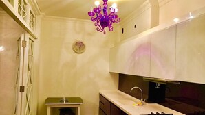 Une cuisine avec des meubles blancs, une cuisinière à gaz, un évier et une petite table.