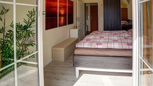 A bedroom with a bed, a bench, a small cabinet, and a wall with three paintings.