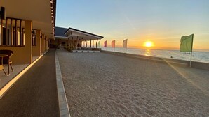 Un hotel frente a la playa con un área de estar techada, una piscina y banderas.