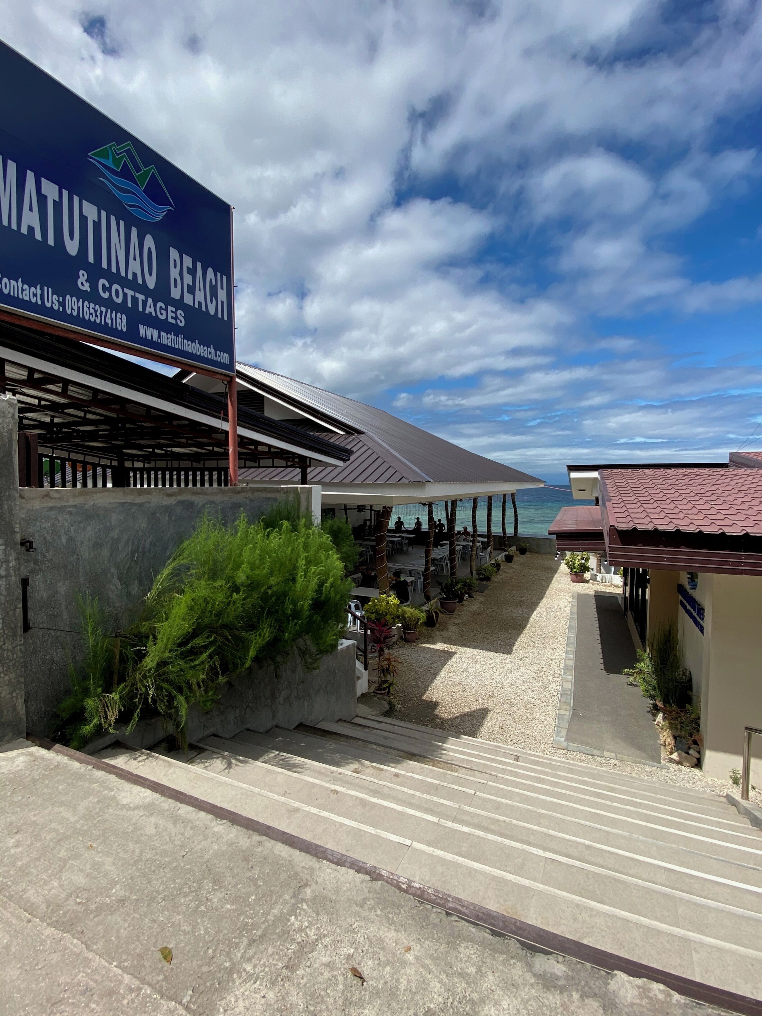 Una propiedad frente a la playa con un letrero que dice Matutina Beach & Cottages, asientos al aire libre y vista al mar.
