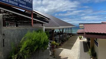 Una propiedad frente a la playa con un letrero que dice Matutina Beach & Cottages, asientos al aire libre y vista al mar.