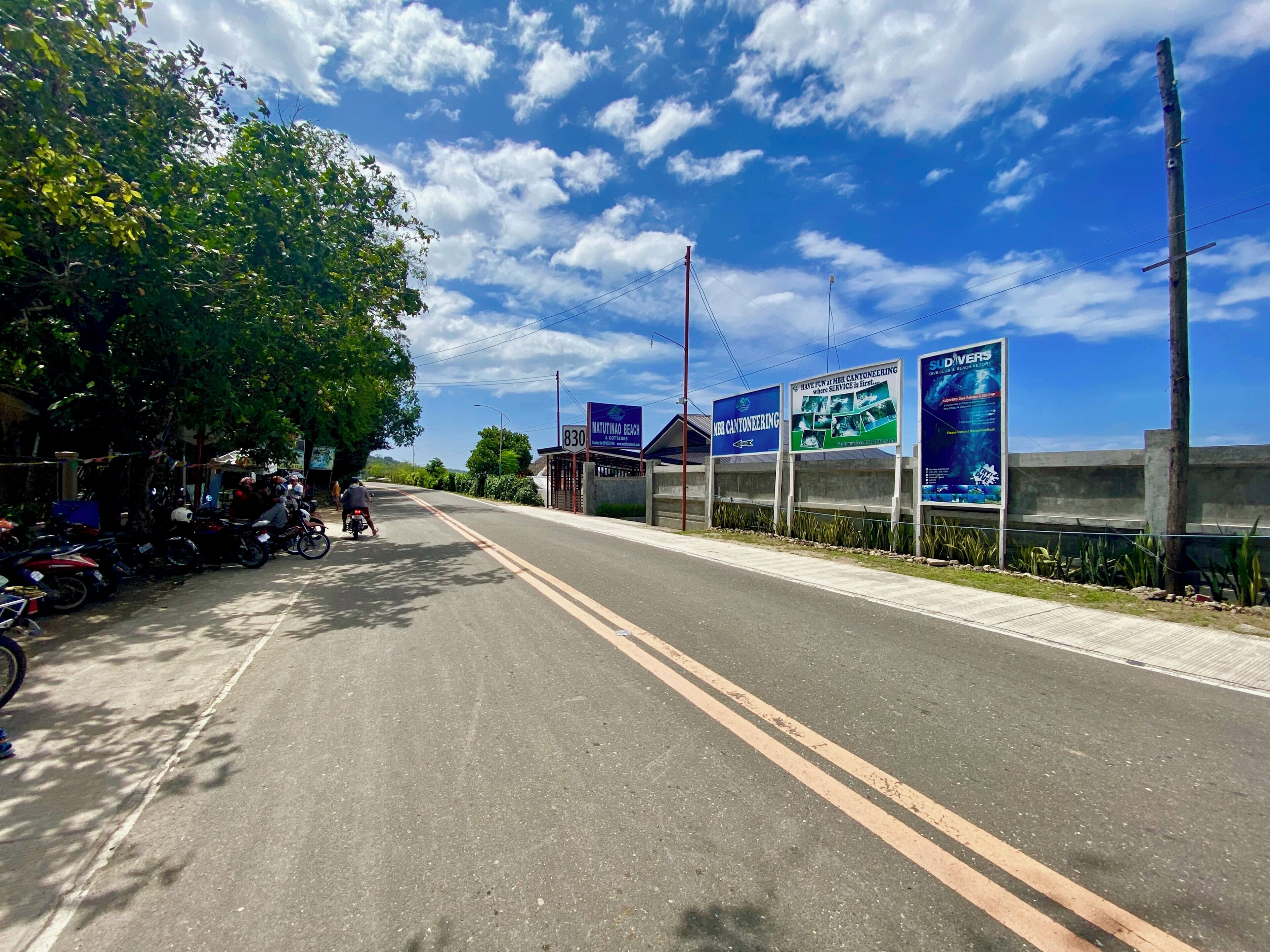 A road with parked motorcycles, a clear sky, and a sign for a resort.