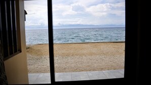 Vista desde una habitación con un ventanal grande que da a una playa y al mar.
