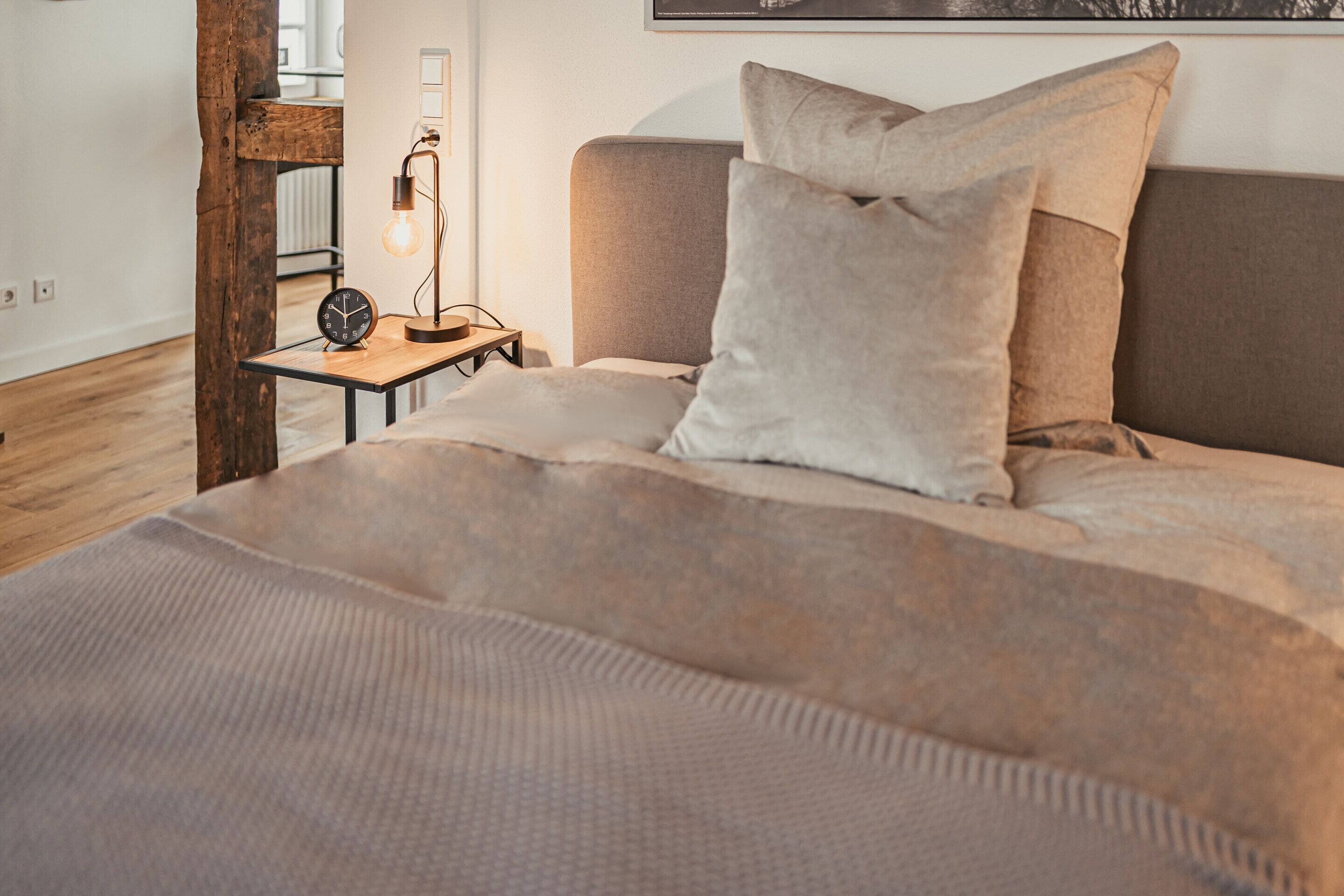 A bedroom with a bed, a nightstand with a lamp, and a wooden chair.
