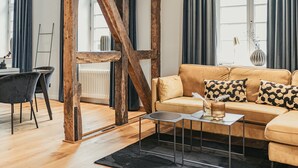 Ein modernes Wohnzimmer mit Holzbalken, einer Couch mit gemusterten Kissen, einem Couchtisch und einem schwarzen Teppich.