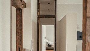 Ein schmaler Korridor mit Holzboden, der zu einem Schlafzimmer mit Bett und Nachttisch führt.