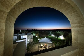 An arched stone structure overlooking a courtyard with a tent and outdoor seating.