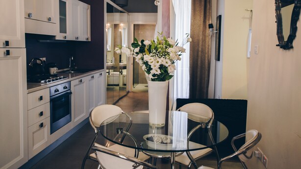 Une cuisine moderne avec des meubles blancs, une table à manger en verre et un lustre.