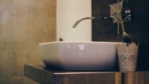 Un lavabo de salle de bain avec un robinet moderne et une plante en pot à côté.