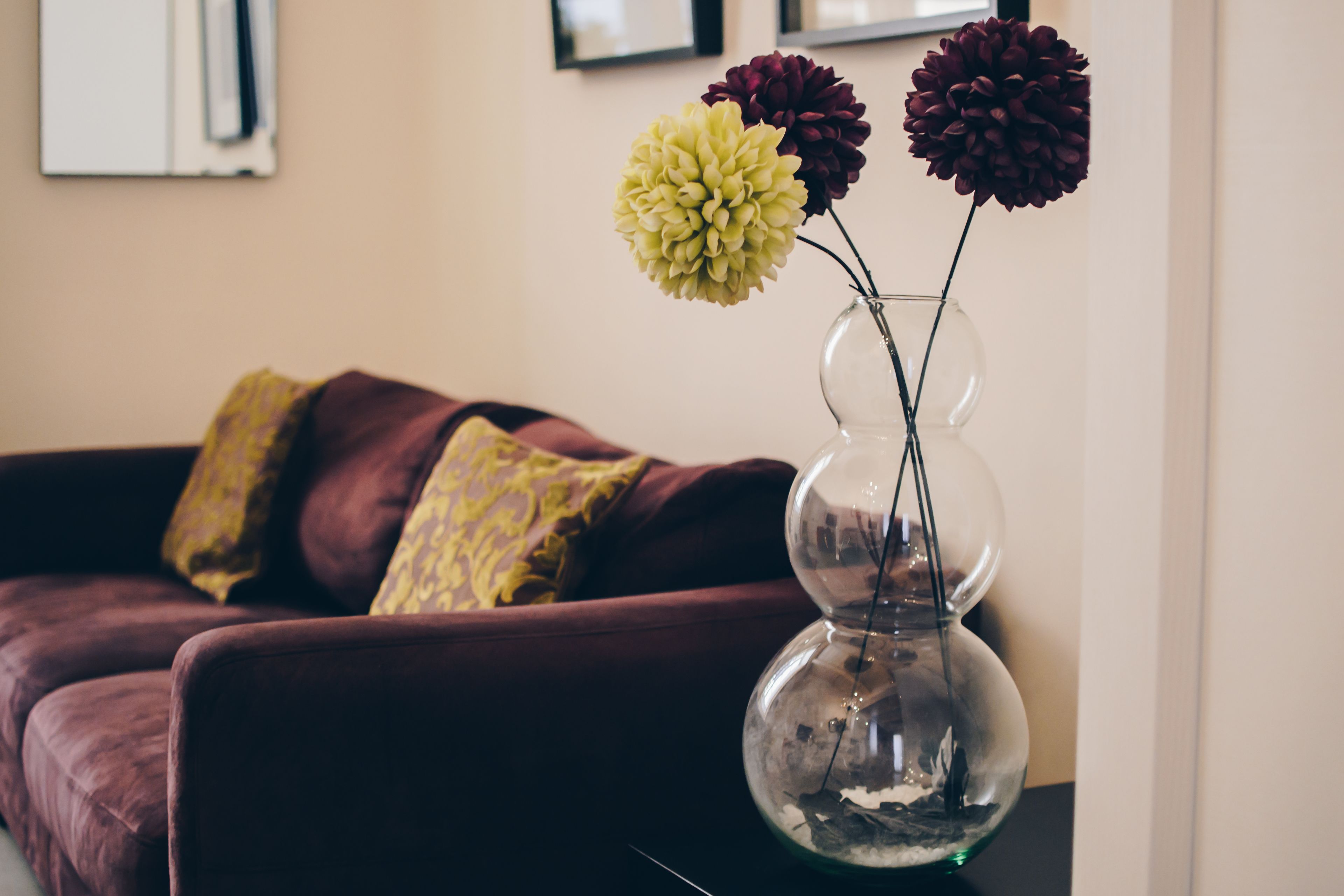 A clear glass vase with flowers on a table in a living room.